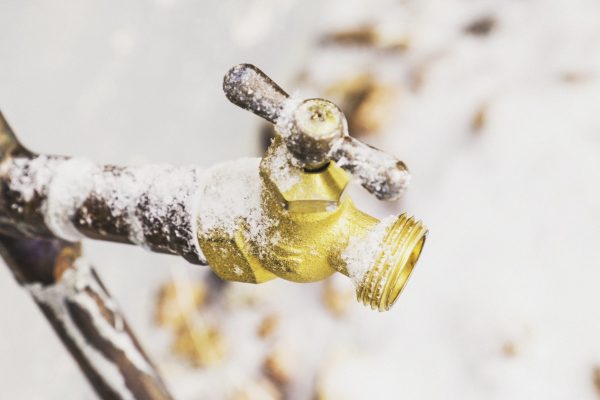 Frozen outdoor water faucet covered in snowflakes